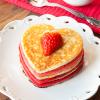 A stack of heart-shaped pancakes with berries on top